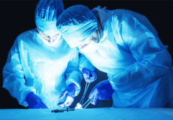 Two surgeons, a man and a woman, perform surgery to remove prostate adenoma and varicocele,...