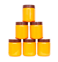 Orange plastic jars with a brown lid are set in a row with a pyramid on a white background, isolate