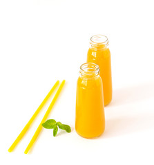 Healthy mango smoothie in a glass with mint and straw isolated on white. Refreshing and tasty smoothies with tropical fruits: mango and banana.