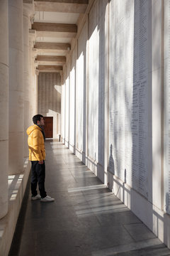 Man looking at fallen soldier names on Menin gate memorial wall