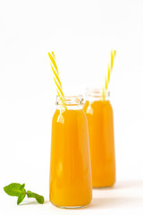 Fresh mango banana smoothie in a glass with mint on white. Refreshing and tasty smoothies with tropical fruits: mango and banana.