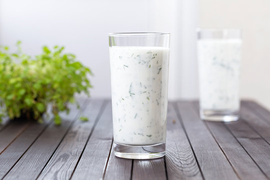 Fresh homemade yogurt (kefir, ayran) in glass with herbs. Ayran, homemade yogurt drink with herbs and cucumbers - healthy summer refreshing cold drink. Probiotic fermented dairy drink. Healthy food. 