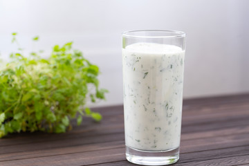 Fresh homemade yogurt (kefir, ayran) in glass with herbs. Ayran, homemade yogurt drink with herbs and cucumbers - healthy summer refreshing cold drink. Probiotic fermented dairy drink. Healthy food. 