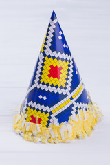 Birthday party carton cone hat. Blue party hat with yellow fringe. Cardboard party decoration.