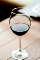 Glass with red wine on a wooden table, blurred background, selective focus. Tasting, restaurant. 