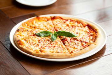 Margherita pizza on wooden background. Italian pizza with mozzarella, cheese and basil leaves. 