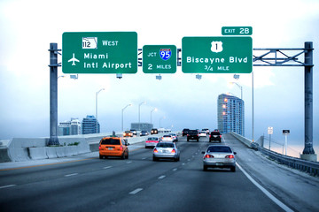 Cars moving on a highway with directional signs to Miami International airport - 272448377