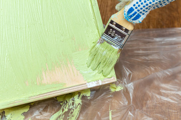 painting wooden tray salver for food in green khaki color with paintbrush process close up