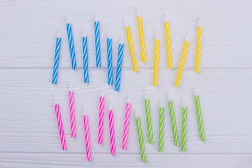 Striped Birthday party candles. Different colors Birthday party candles on white wood. Celebration party objects.