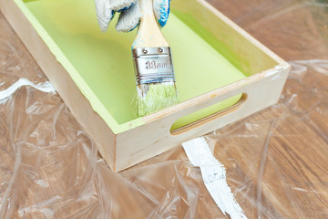 painting wooden tray salver for food in green khaki color with paintbrush process close up