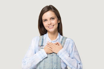 Attractive young woman holding hand on heart feels gratitude