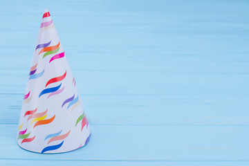 Party cone hat with copy space. White Birthday cap on blue wooden boards with copy space.