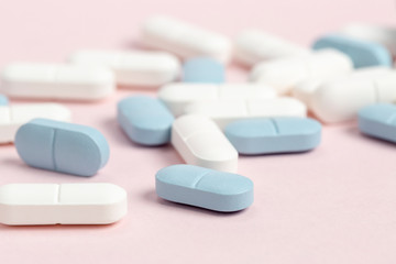White and blue medical pills on a pink background