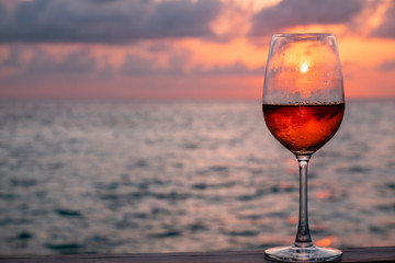 A glass of red wine on sunset background at the Maldives