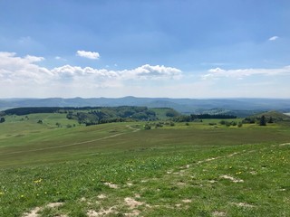 Fototapeta na wymiar Scenic hike to the pilgrimage site Kreuzberg (Calvary) in Bavaria's Röhn (Roehn) region (Germany): panoramic views from the sacred mountain on a sunny summer day with lush green landscape & a blue sky