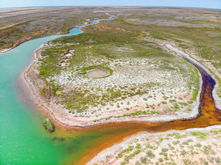 Amazing aerial view of small red water river and green water lake in Baskunchak