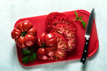 sliced Beefsteak tomato on a red cutting board and a knife. cooking healthy summer meals