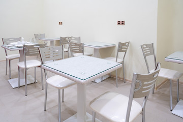 Dining tables with chairs in a light beige room.