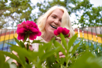 Fototapeta premium happy senior european woman with flowers blooming at summer garden