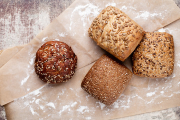 Gold rustic crusty loaves of bread and buns on wooden background. Still life captured from above top view, flat lay.