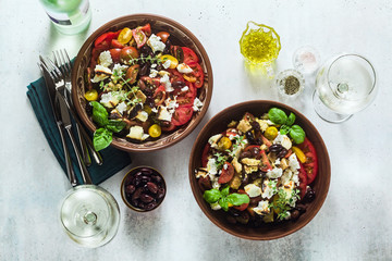 Italian traditional Tuscan panzanella salad with fresh tomatoes and cheese in clay plates and white wine in a bottle and glasses . authentic Mediterranean healthy food