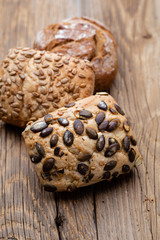 Gold rustic crusty loaves of bread and buns on wooden background. Still life captured from above top view, flat lay.