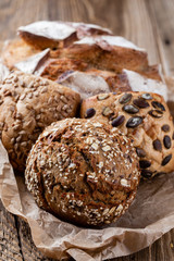 Gold rustic crusty loaves of bread and buns on wooden background. Still life captured from above top view, flat lay.