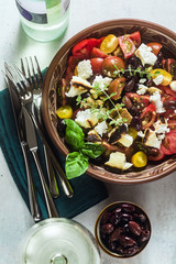 Italian traditional Tuscan panzanella salad with fresh tomatoes and cheese in clay plates and white wine in a bottle and glasses . authentic Mediterranean healthy food