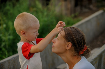 Fototapeta premium Country boy gently hugs beautiful mother. child is happy in village on vacation with mom