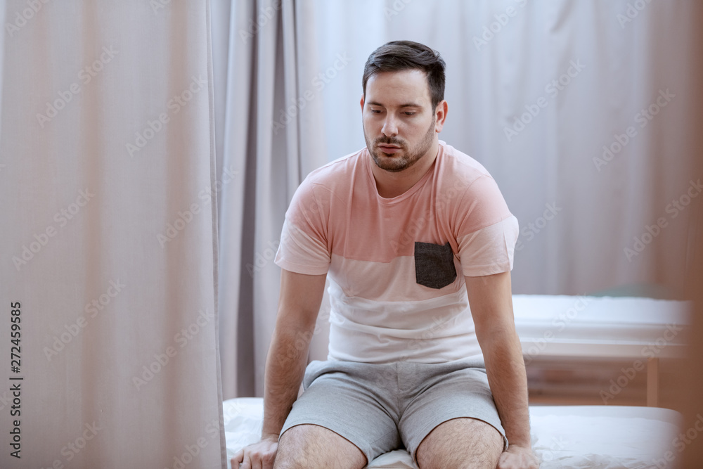 Wall mural upset caucasian patient sitting on hospital bed and waiting for examine results.