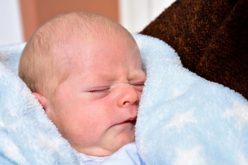 Newborn baby with a blue blanket. Blonde boy.