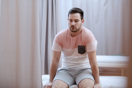 Upset Caucasian Patient Sitting On Hospital Bed And Waiting For Examine Results.