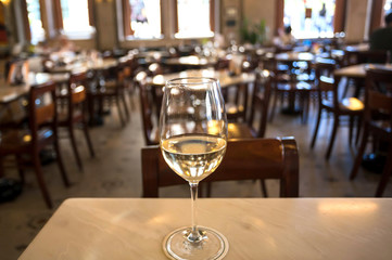 White wine glass on table of huge empty restaurant in retro style. Leisure concept
