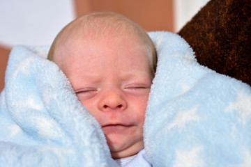 Newborn baby with a blue blanket. Blonde boy.