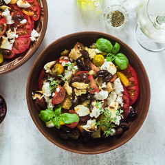Italian traditional Tuscan panzanella salad with fresh tomatoes and cheese in clay plates and white wine in a bottle and glasses . authentic Mediterranean healthy food