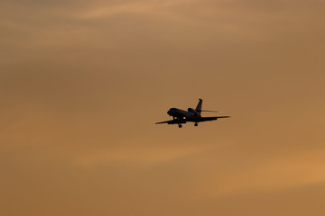 Fototapeta na wymiar Plane preparing for landing with colorful sky at sunset