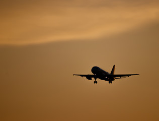 Silhouette of a plane prepared for landing at sunset