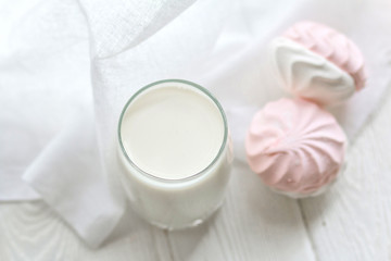 Glass of milk and marshmallows on a white table. Top view. 