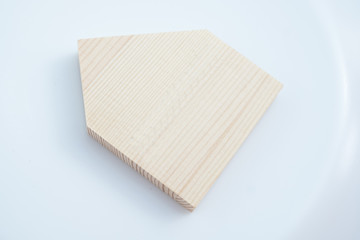 white background of paper cutout in simple house shape by brown wooden plate, for home and insurance conceptual. place for inscription