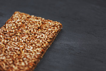 Useful snacks. Fitness diet food. Boletchik from kozinaki sunflower seeds, energy bars. Black textural background Top view. Copy space