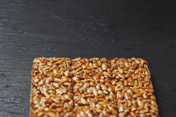 Useful snacks. Fitness diet food. Boletchik from kozinaki sunflower seeds, energy bars. Black textural background Top view. Copy space