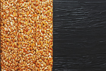 Useful snacks. Fitness diet food. Boletchik from kozinaki sunflower seeds, energy bars. Black textural background Top view. Copy space