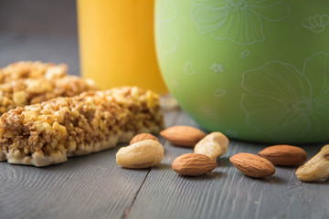 Granola cereal flakes with dried fruit, nuts in green bowl on gray wooden table.