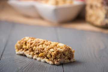 Granola bars cereal flakes with dried fruit, nuts on gray wooden table.