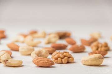 Assortment of nuts on white wooden table. Cashew, hazelnuts, walnuts, almonds.