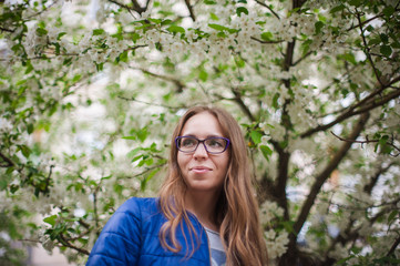 Beautiful woman portrait in the blooming garden of apple