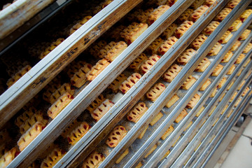 Puff buns with berry jam are on metal shelves. Preparation of pastries at the confectionery factory. Sweet dessert of dough. © Yashkin Ilya