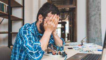 Desperate stressed out engineer sitting at desk with laptop. Failed connection, unsuccessful experiment.