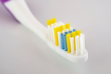 Tooth-brush with purple handle over white. Shallow DOF
