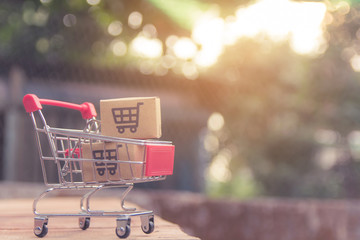 Shopping concept - Cartons or Paper boxes in shopping cart on brown wood table. online shopping consumers can shop from home and delivery service. with copy space